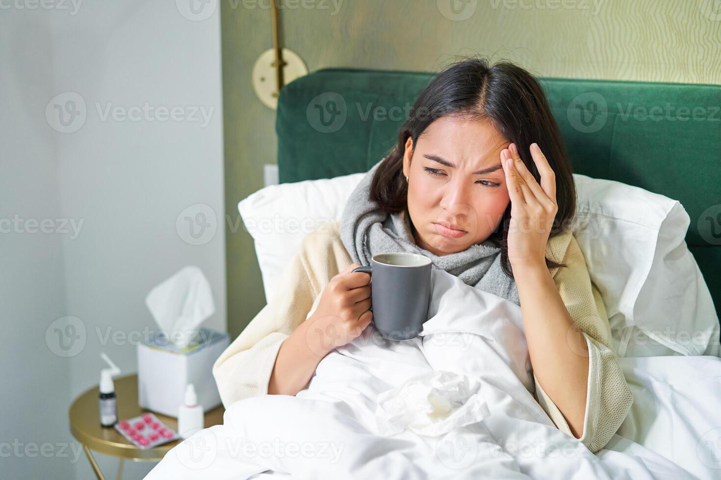 influensa, sjukdom och människor. ung kvinna känsla sjuk, har feber och fångst col, liggande i säng med varm te, tar läkemedel från influensa foto