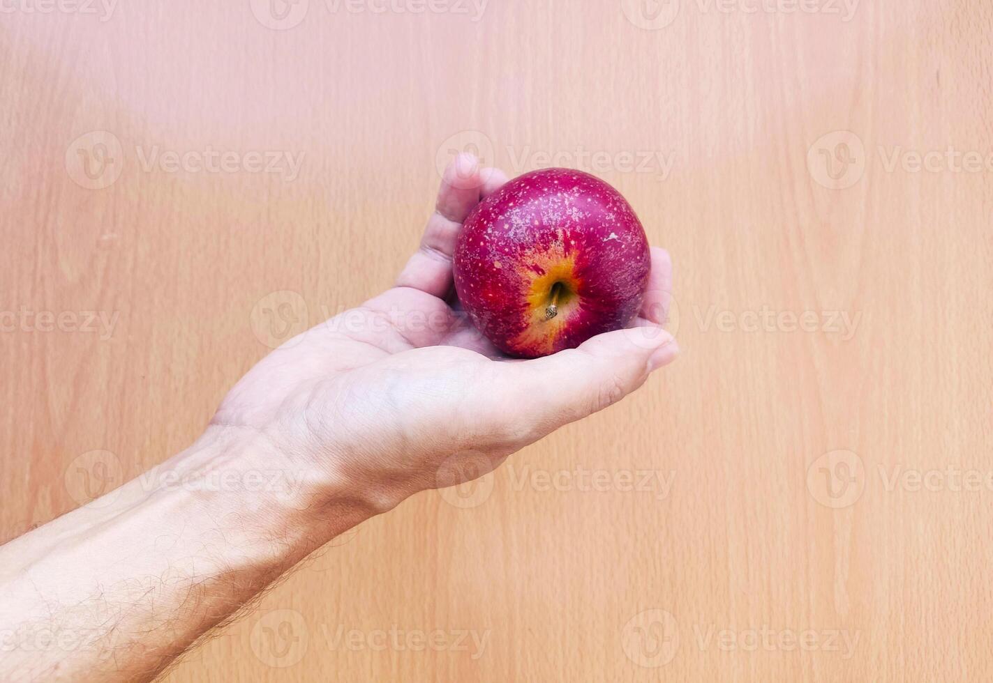 stänga upp av man händer innehav röd äpple ovan en skrivbord. foto