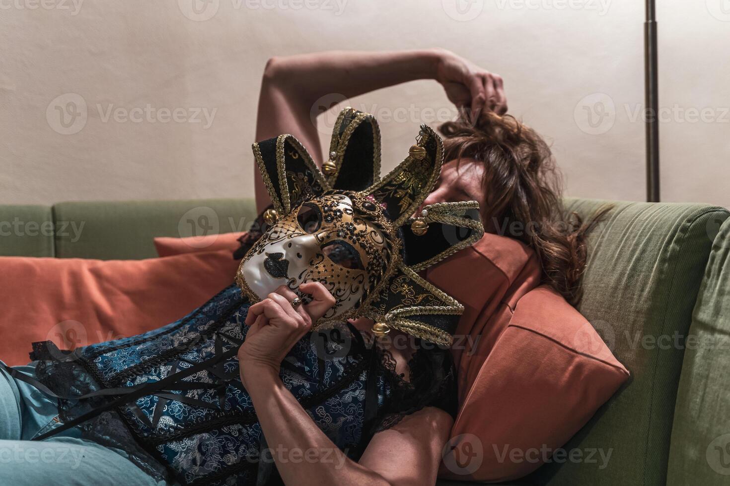 attraktiv kvinna bär en mask Framställ liggande på de soffa på Hem foto