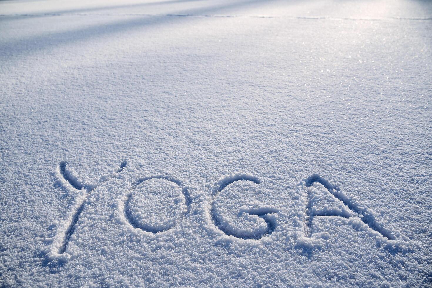 de ord yoga är skriven i de snö. vinter- yoga i de morgon- Sol. en minimalistisk bild av zen buddhism. fred och lugn. foto