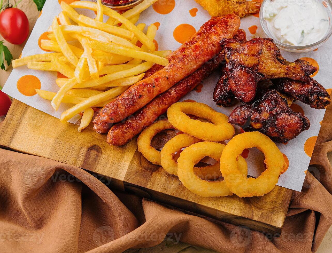 franska frites potatisar med lök ringar, korvar, krutonger och kryddad kyckling ben foto