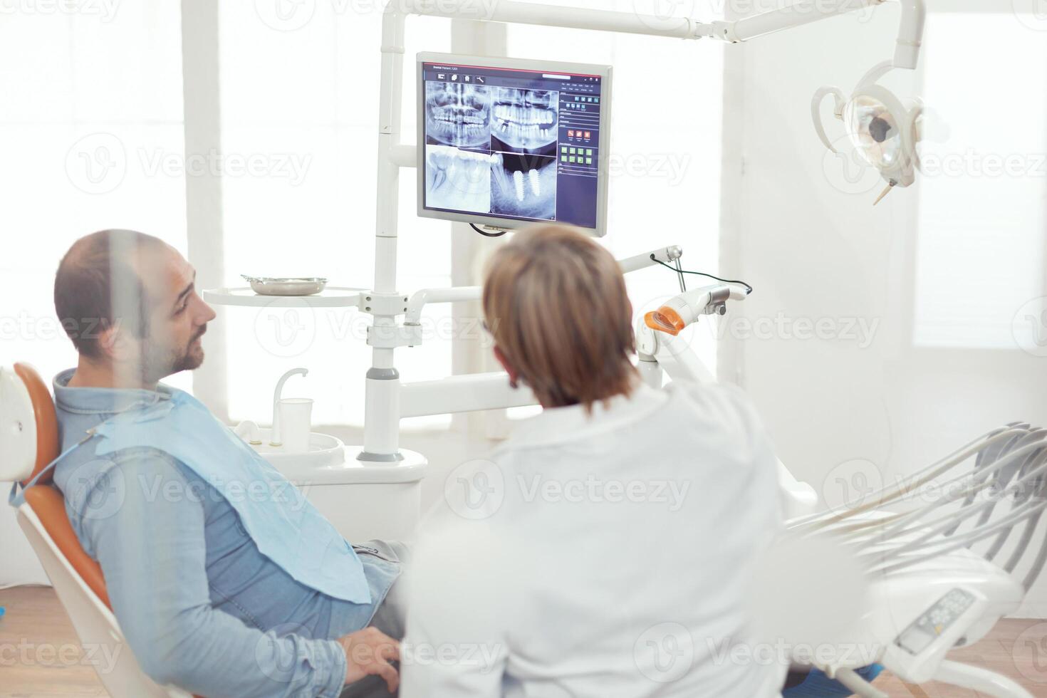 tandläkare läkare och patient ser på digital teeh röntgen i stomatologi sjukhus kontor. sjuk patient Sammanträde på dental stol framställning för tandvård kirurgi under somatologi utnämning foto