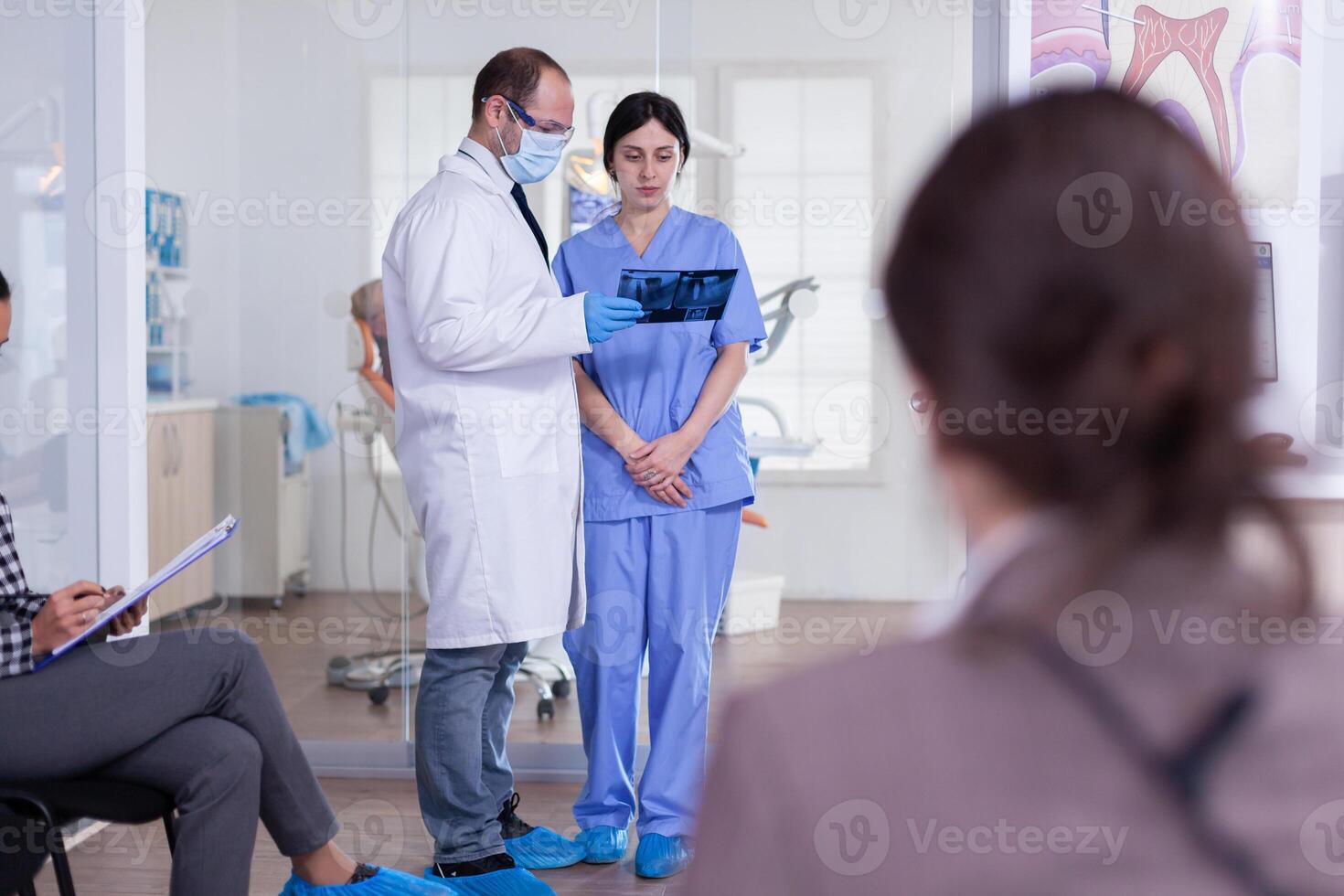 tandläkare läkare innehav tänder röntgen och sjuksköterska lyssnande diagnos i stomatologi sjukvård reception. människor fyllning tandvård form i väntar område. foto