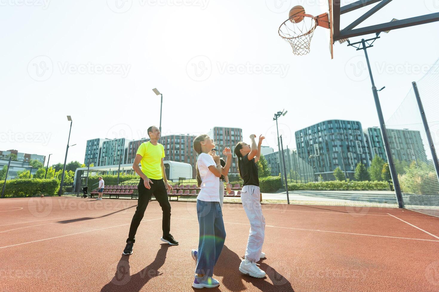 sommar högtider, sport och människor begrepp - Lycklig familj med boll spelar på basketboll lekplats foto