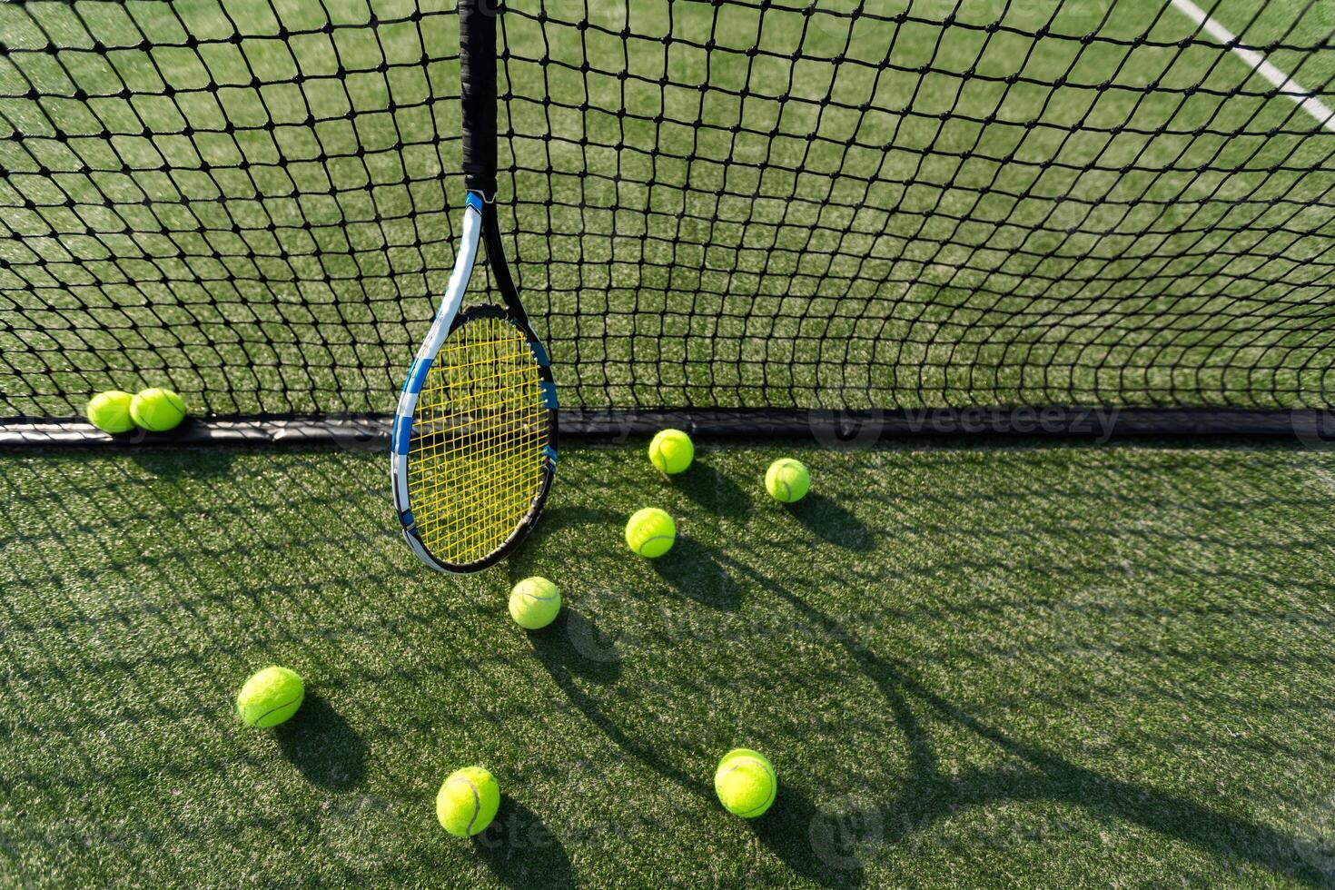 tennis racket liggande på netto med tennis boll i hård yta domstol foto