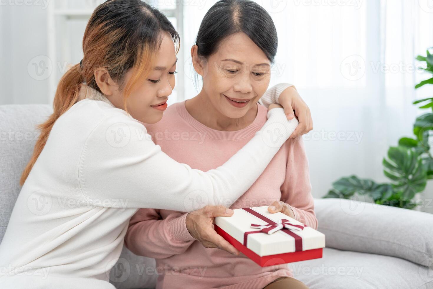 mor dag, söt asiatisk tonåring flicka ge gåva låda till mogna mitten ålder mamma. kärlek, kyss, vård, Lycklig leende njut av familj tid. fira särskild tillfälle, Lycklig födelsedag, Lycklig ny år, glad jul foto