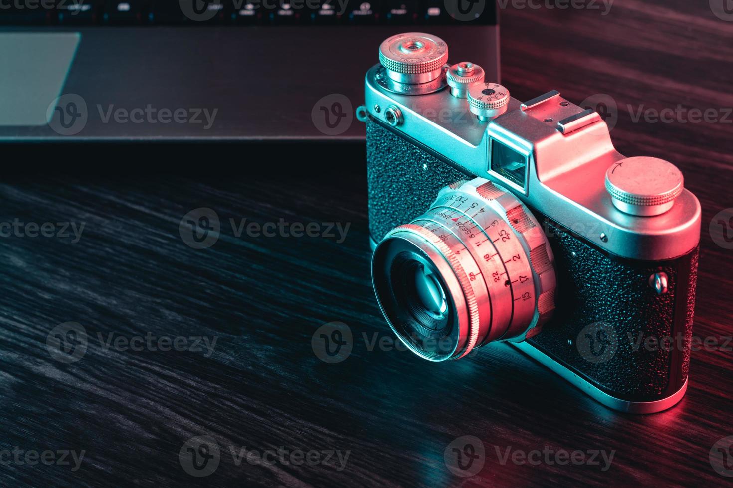 gammal filmkamera och laptop på bordet. blått och rött ljus. se foto
