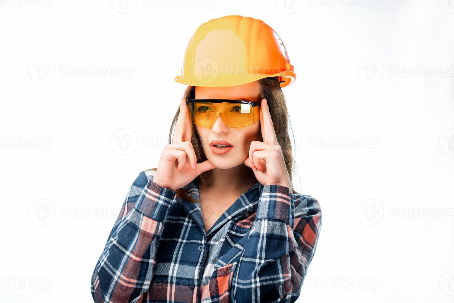Söt kvinna bär orange skyddande hjälm och glasögon har huvudvärk och innehav fingrar på huvud isolerat på vit bakgrund. trött kvinna byggare i säkerhet hjälm foto