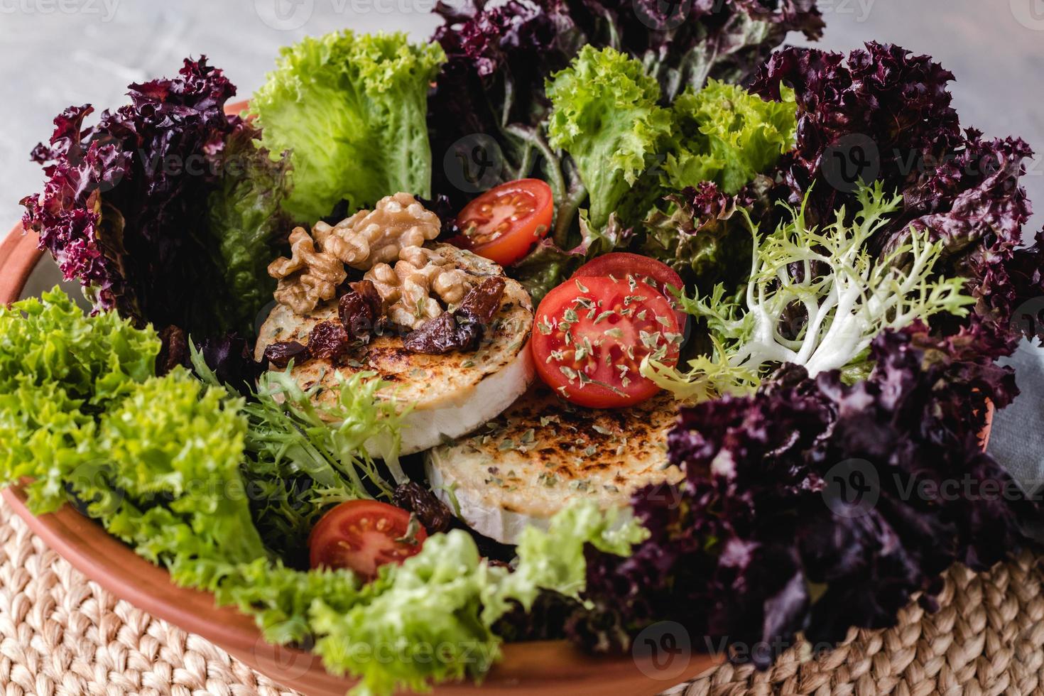 sallad med sallad, körsbärstomater, getost, nötter och kryddor foto