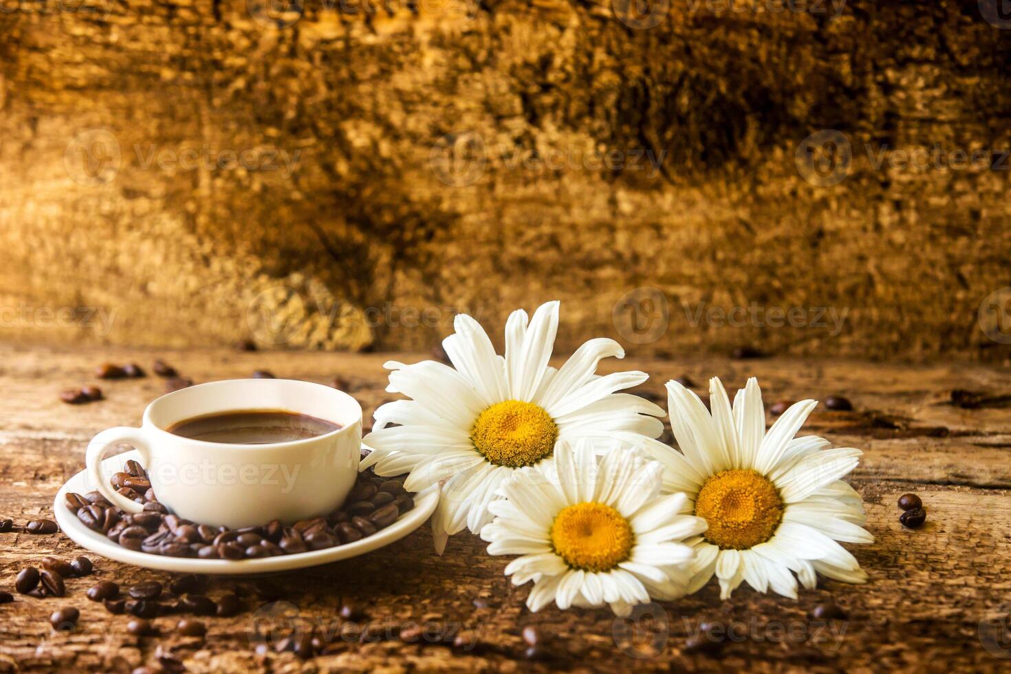 kaffe kopp och friterad kaffe bönor på en trä- tabell med skön vit blommor på en trä bakgrund foto