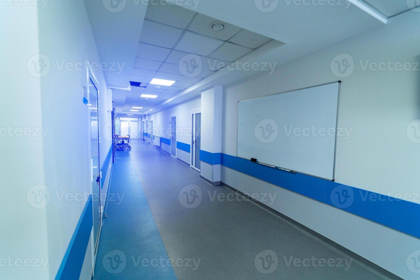 lång sjukhus hall i ljus vit och blå färger. många dörrar och whiteboard på vägg. foto