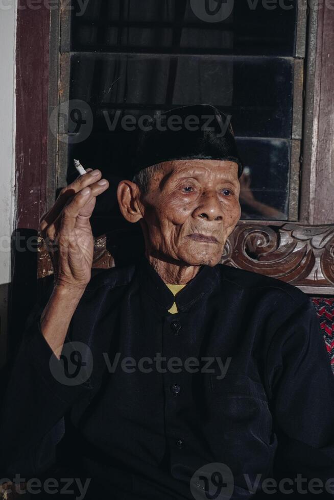 porträtt av ett äldre asiatisk man rökning en cigarett. foto