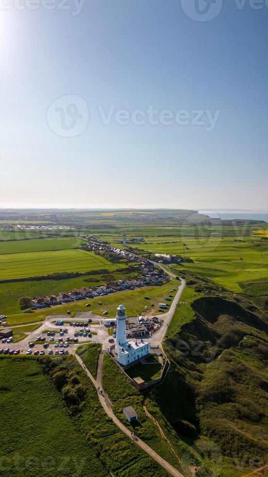 antenn se av en kust fyr med omgivande grönska och klar blå himmel i Flamborough, England foto