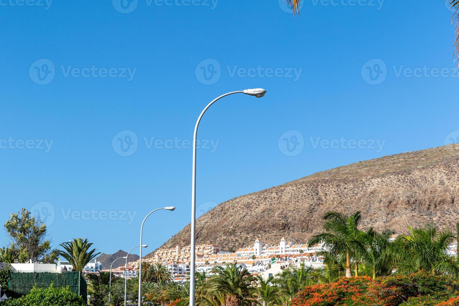 solig förorts landskap med gata lampor och sluttning hem under en klar blå himmel i los cristianos, teneriffa. foto