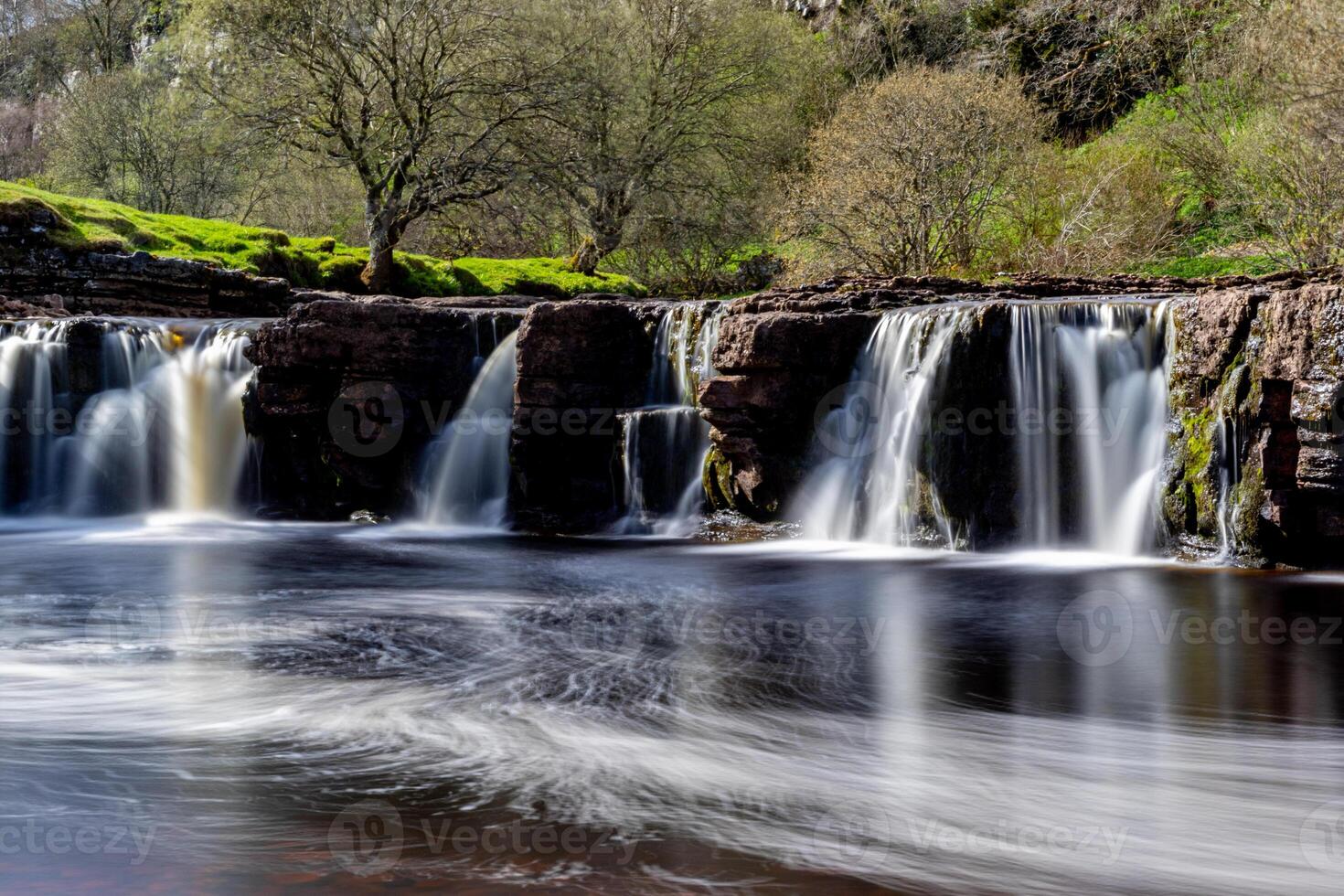 lugn vattenfall med slät vatten strömma i en frodig grön landskap i yorkshire dalar. foto