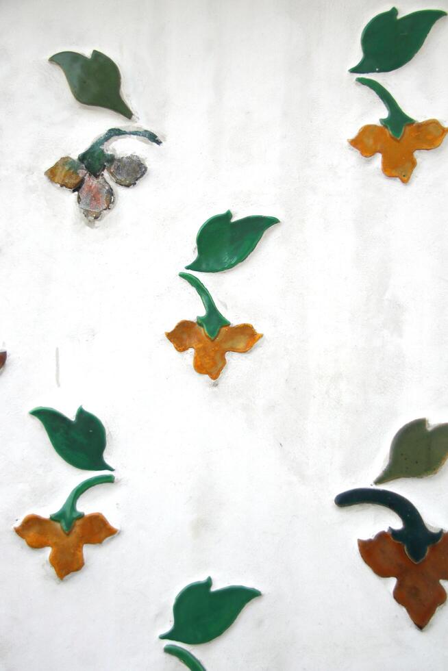 blommor och blad på vit vägg av historia webbplats i tempel, inföding gammal konst i Bangkok, Thailand. foto