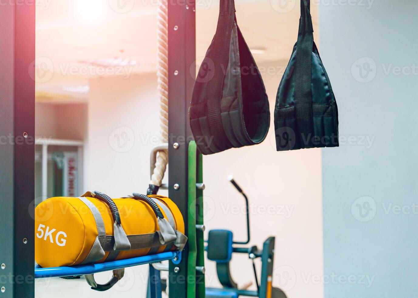 Träning remmar trx hängande från de vägg och stansning gul väska med 5 kg i Gym. Träning utrustning träna objekt för friska och krigisk konst foto