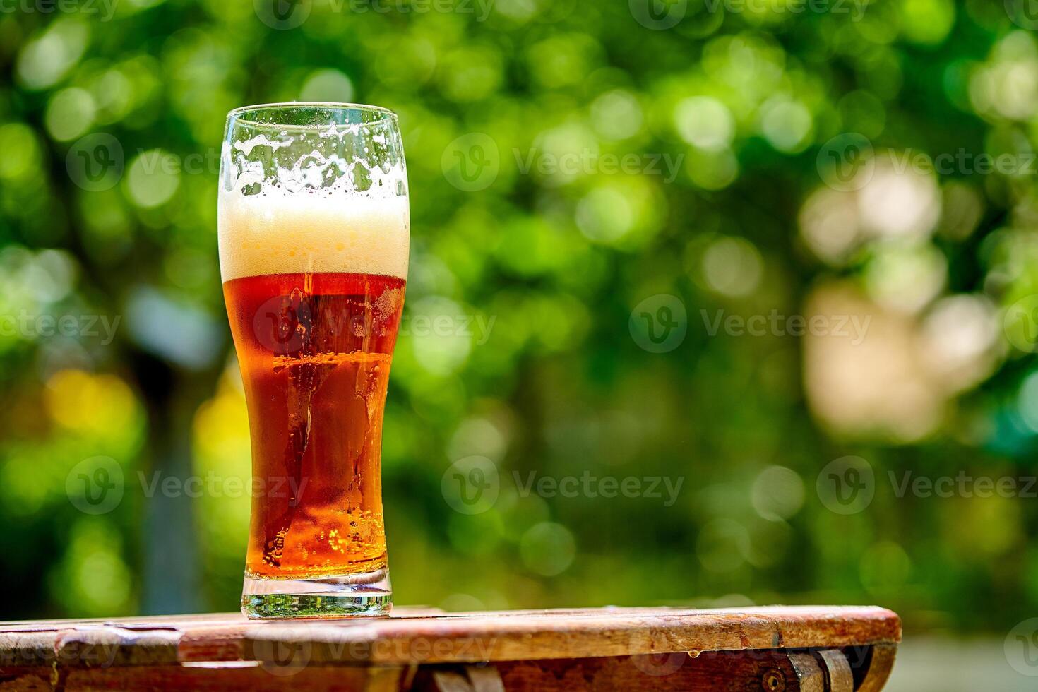 glas av ljus öl på de trä- tabell. bubblor och skum i en glas av ljus öl foto