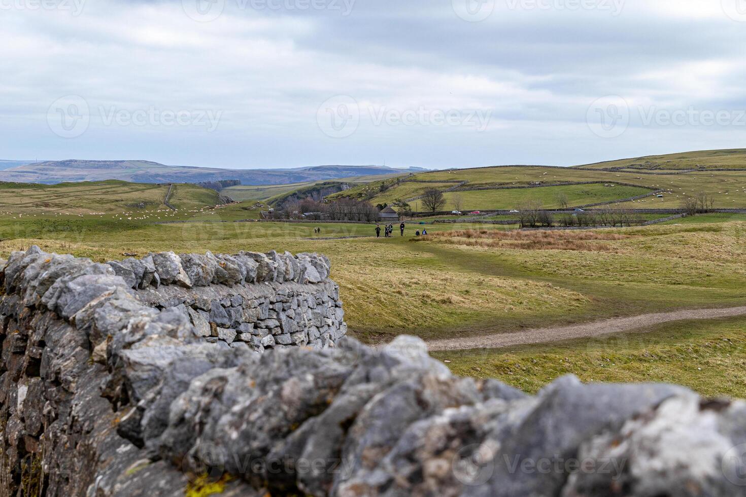 rustik sten vägg med en suddig bakgrund av rullande grön kullar och en klar himmel, skildrar lugn lantlig landskap i topp distrikt, england. foto