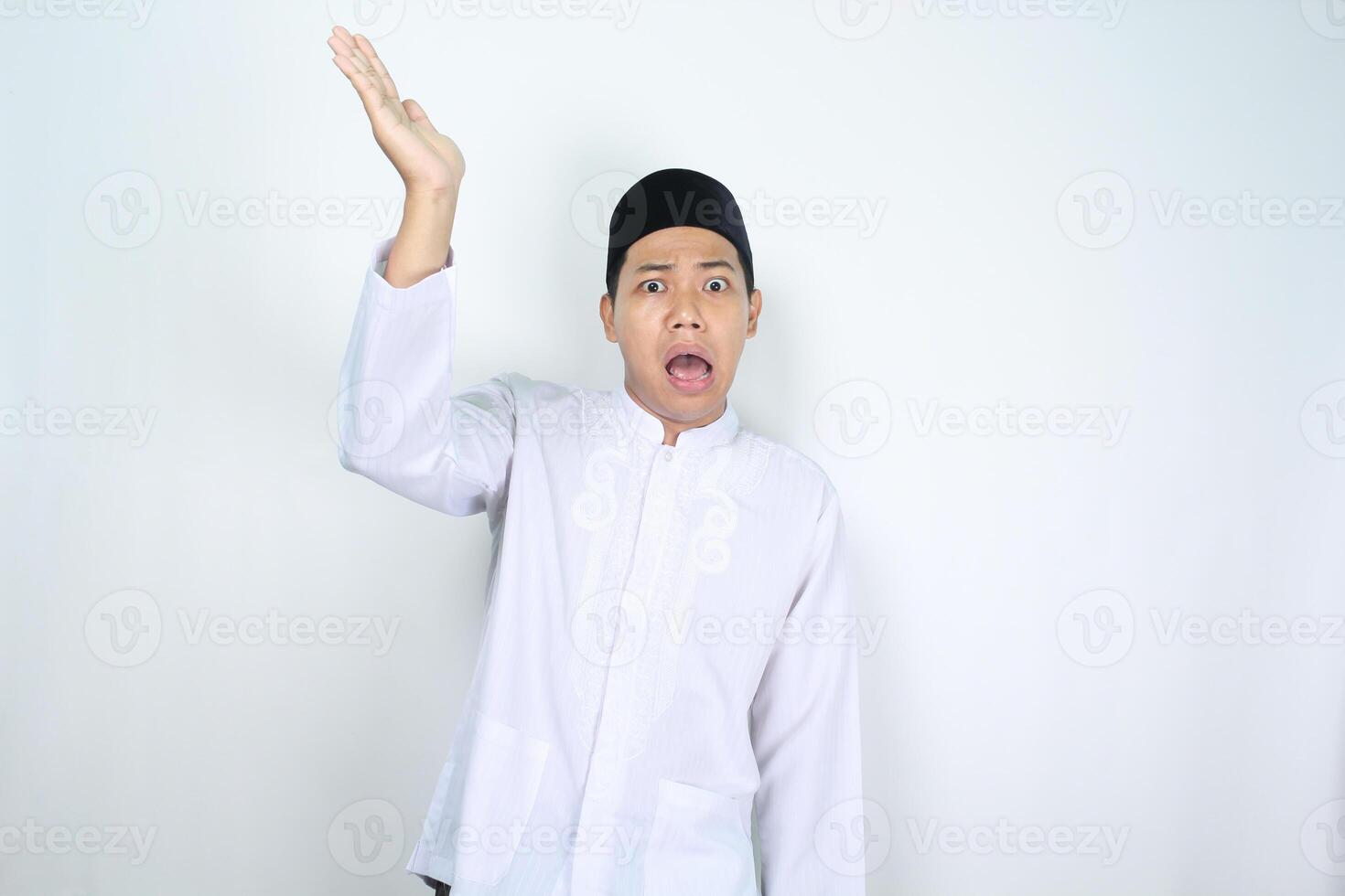 asiatisk man muslim höjning hand till presenter något ovan med chock ansikte uttryck isolerat på vit bakgrund foto