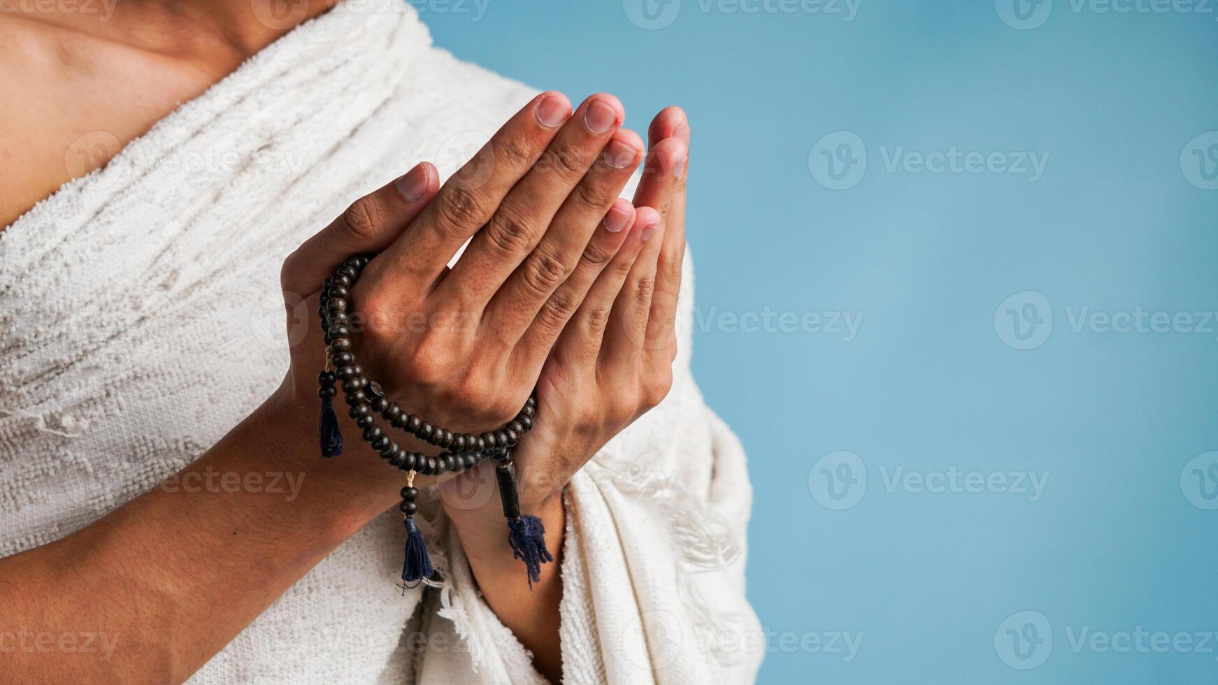 muslim man bär Ihram kläder är bön- med bön pärlor i hans händer foto