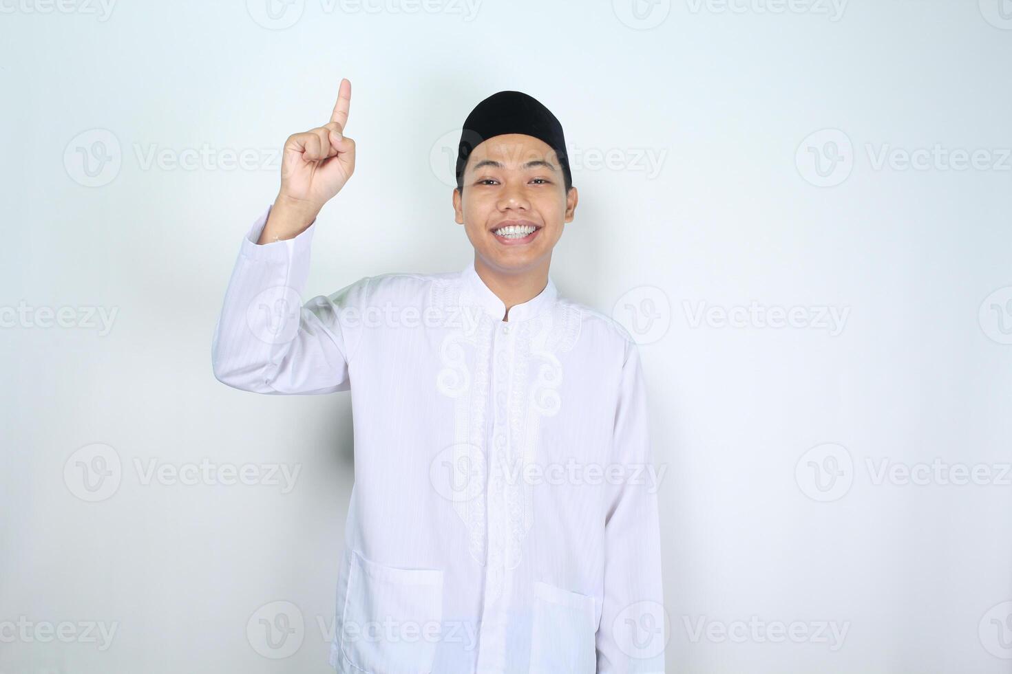 Lycklig muslim asiatisk man pekande upp isolerat på vit bakgrund foto