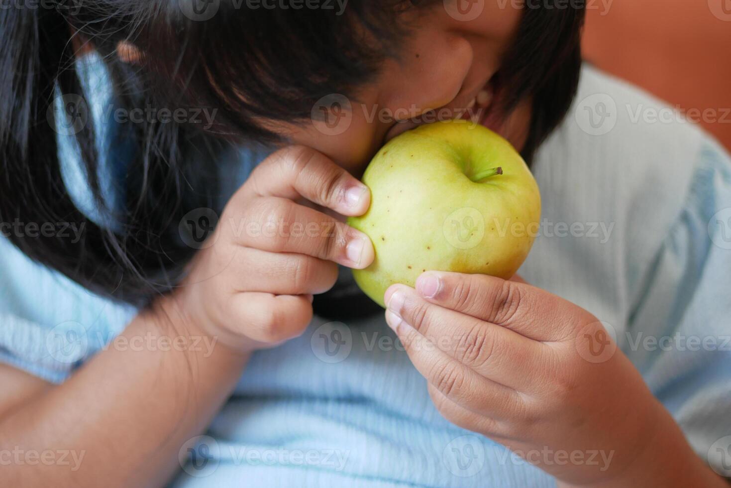 flicka bitande och äter grön äpple foto