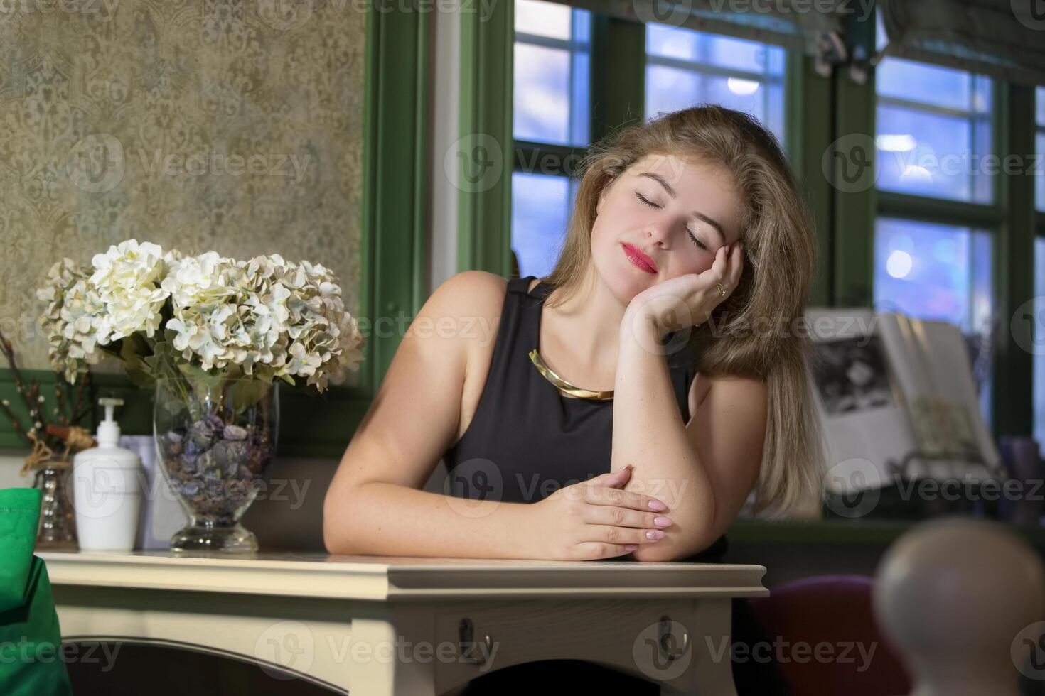 skön blond flicka i en Kafé stängd henne ögon och drömmar. de romantisk skönhet är ensam i de restaurang. foto