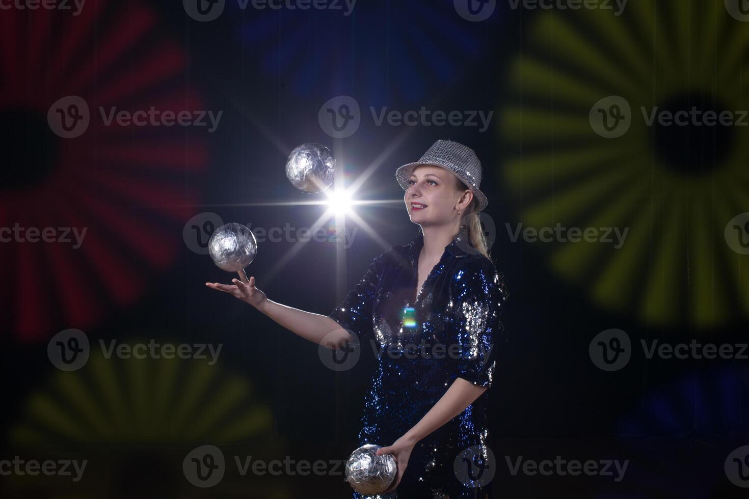 cirkus skådespelerska utför. de flicka jonglerar bollar på en mörk bakgrund i de strålkastare. foto