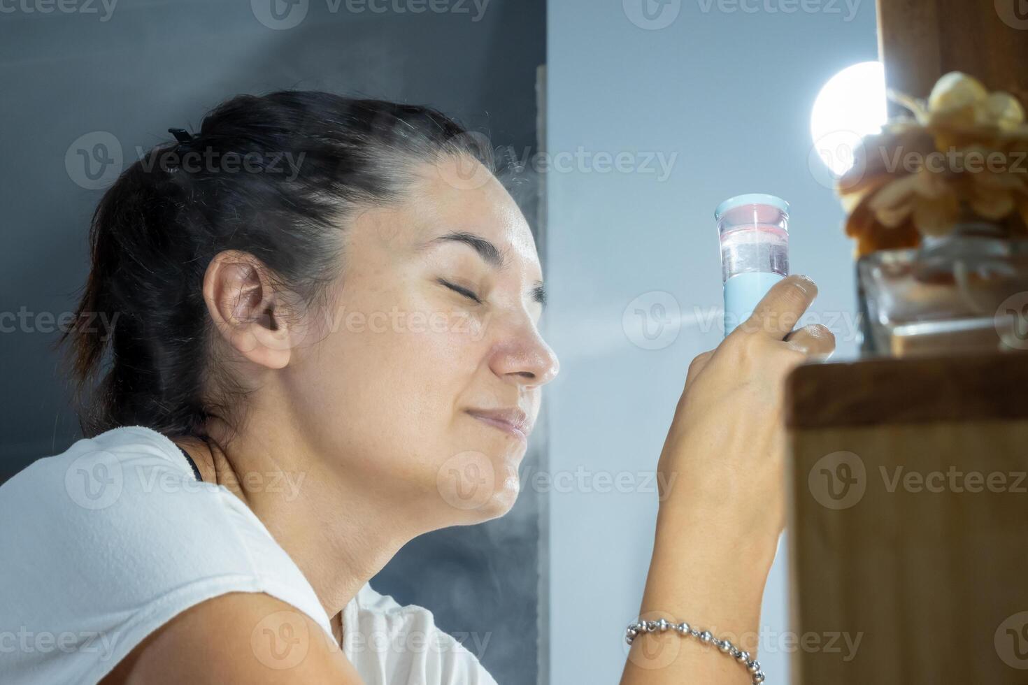 kvinna använder sig av en ansiktsbehandling ångkokare i henne dagligen ansiktsbehandling skönhet rutin. dagligen hud vård, hydratisering och dermatologi. Hem förångare. foto