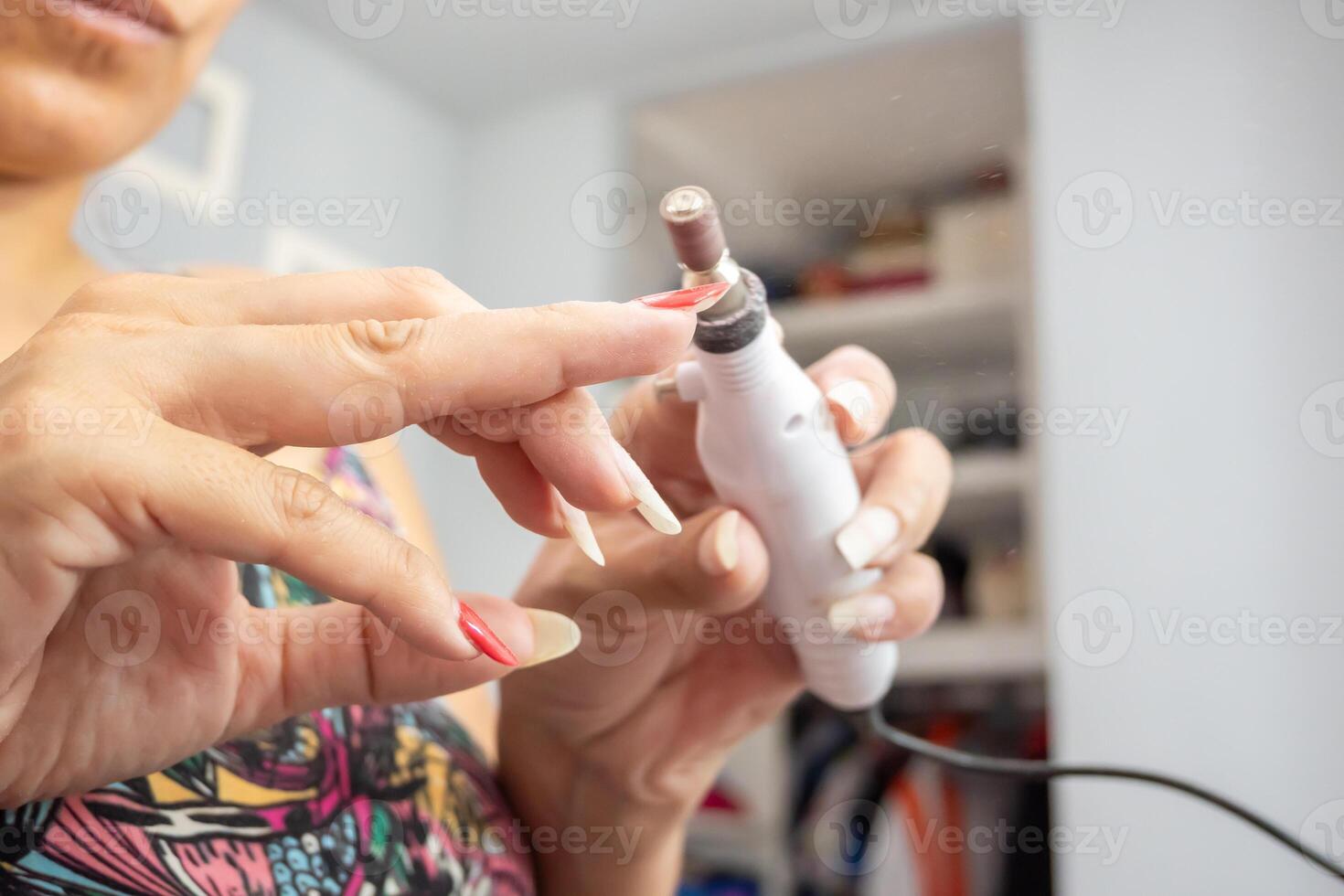 kvinna tar bort de semipermanent nagel putsa från henne naglar med en sandning hjul. foto