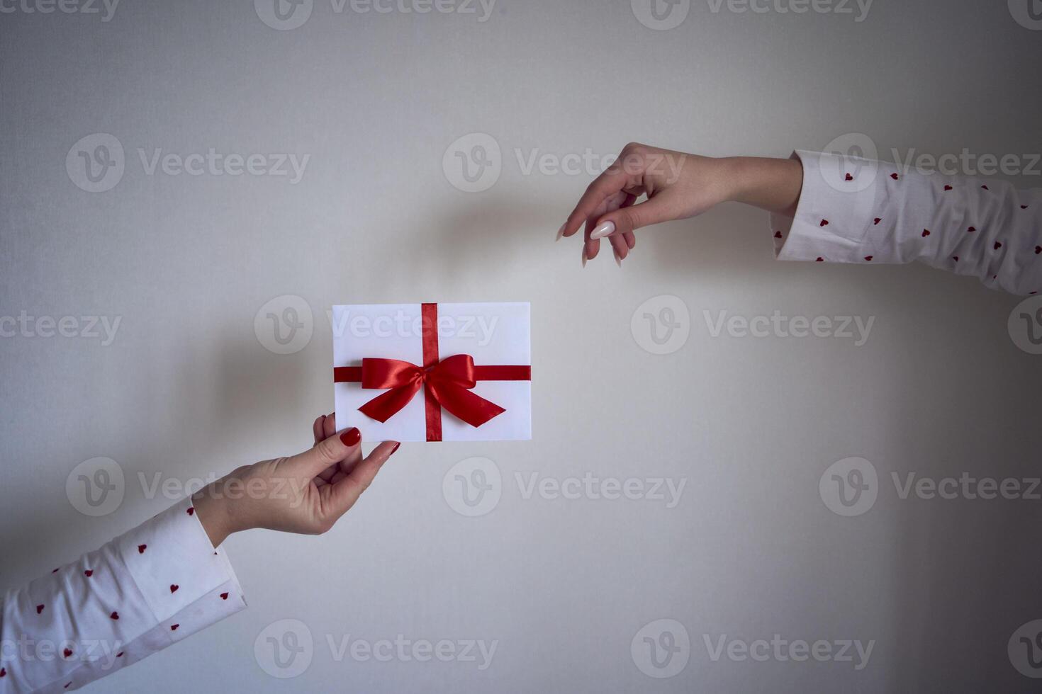 en gåva certifikat i röd och vit färger i kvinna händer på en vit vägg foto