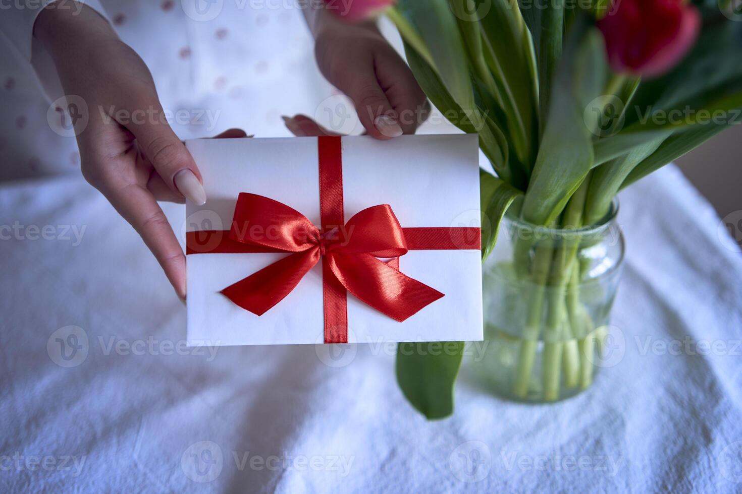 gåva certifikat i röd och vit färger i kvinna händer med röd tulpaner foto