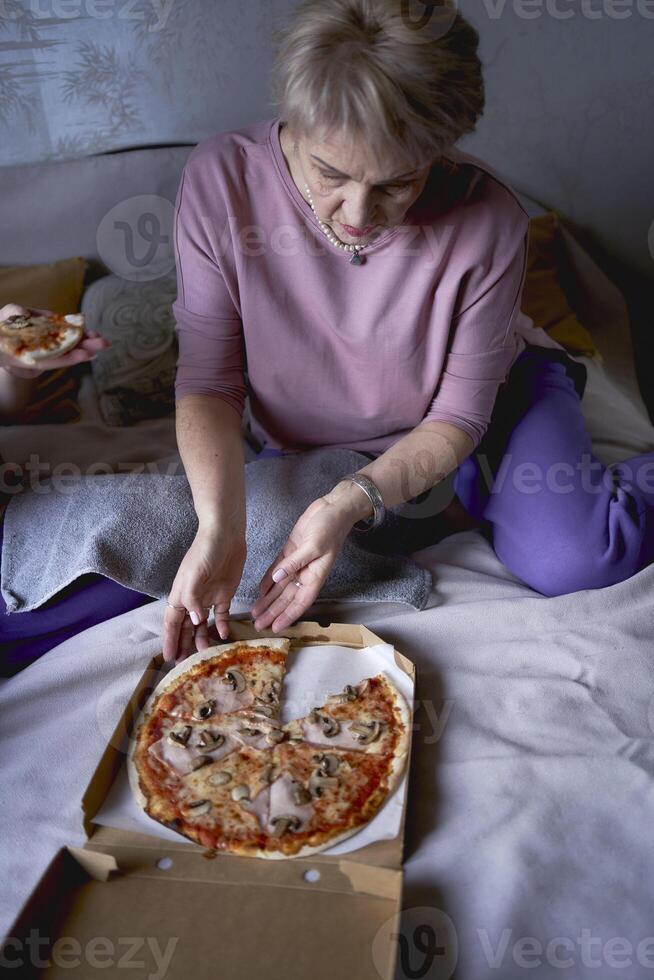 gammal mor och medelålders dotter äter pizza och tittar på en film på Hem foto