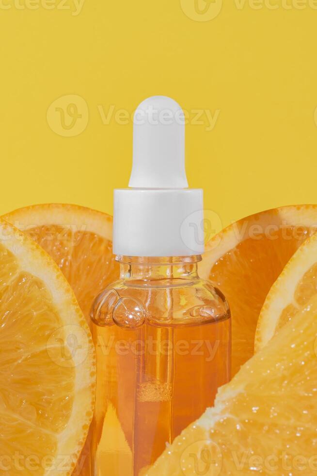 ljus gul bakgrund med en dropper flaska av citrus- infuserad ansikte serum med vitamin c och färsk orange skivor symboliserar hudvård förmåner. mockup, hud vård. foto