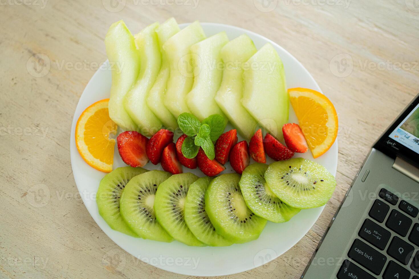 blandad frukt tallrik som innehåller melon, jordgubbar, apelsiner och kiwi foto