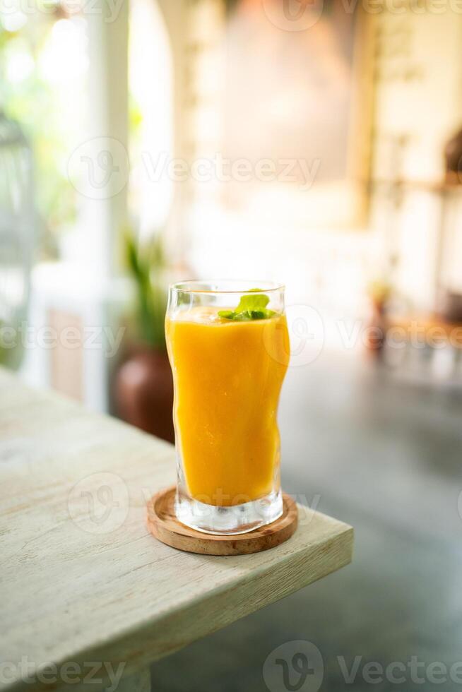 färsk mango juice på tabell med lyx Hem fläck bakgrund foto