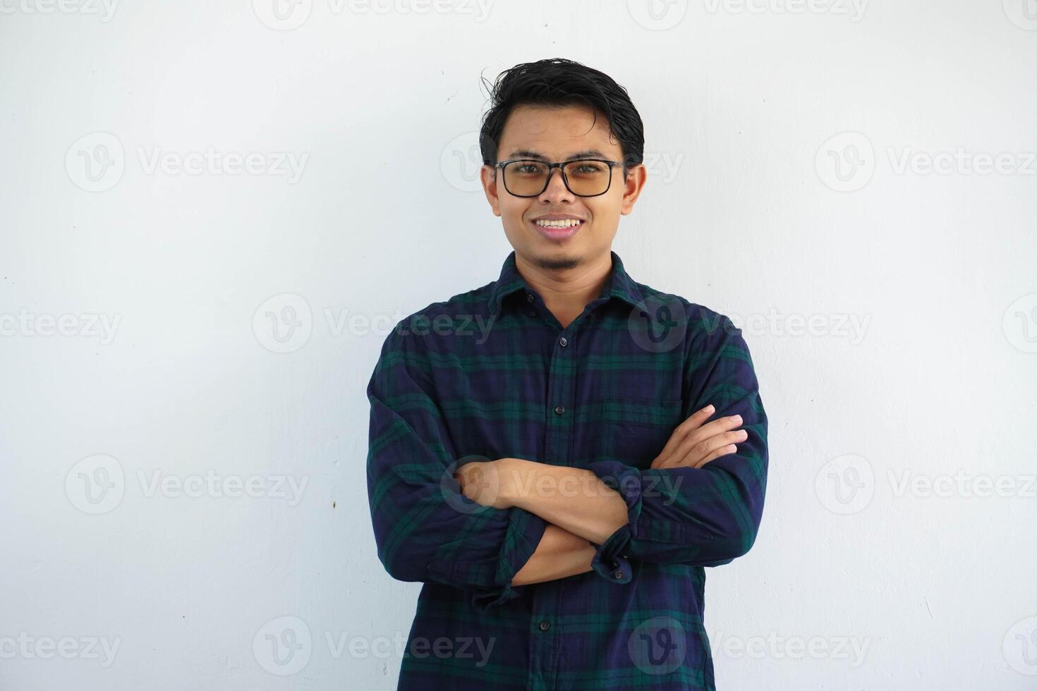 leende ung asiatisk man som visar Lycklig uttryck stående självsäker med vapen korsade isolerat på vit bakgrund foto