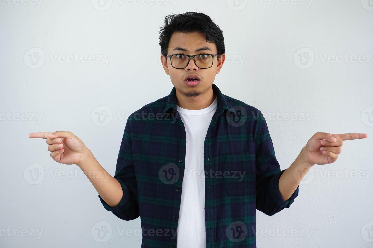 ung asiatisk man som visar förvånad uttryck medan pekande till de vänster och rätt sida isolerat på vit bakgrund foto