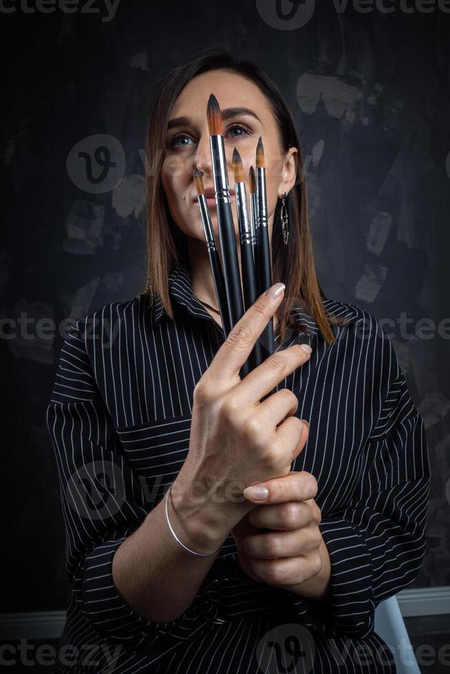 porträtt av en kvinna konstnär, med borstar i henne händer. foto