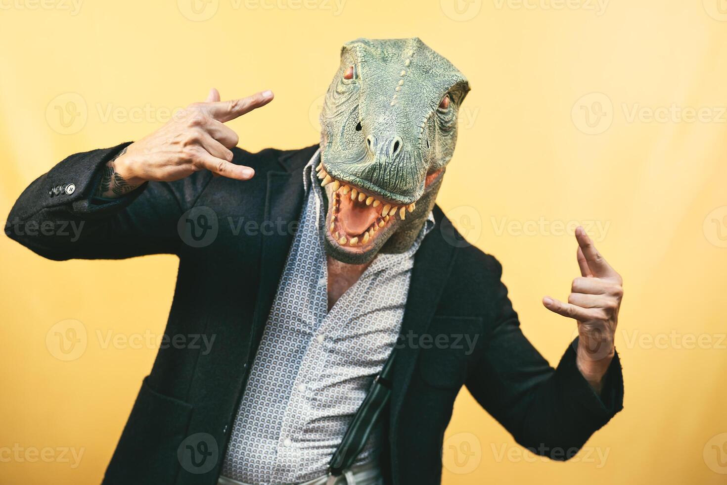 senior man bär t Rex dinosaurie mask - galen hipster kille har roligt fira karneval högtider - absurd och overkligt rolig begrepp - gul bakgrund foto