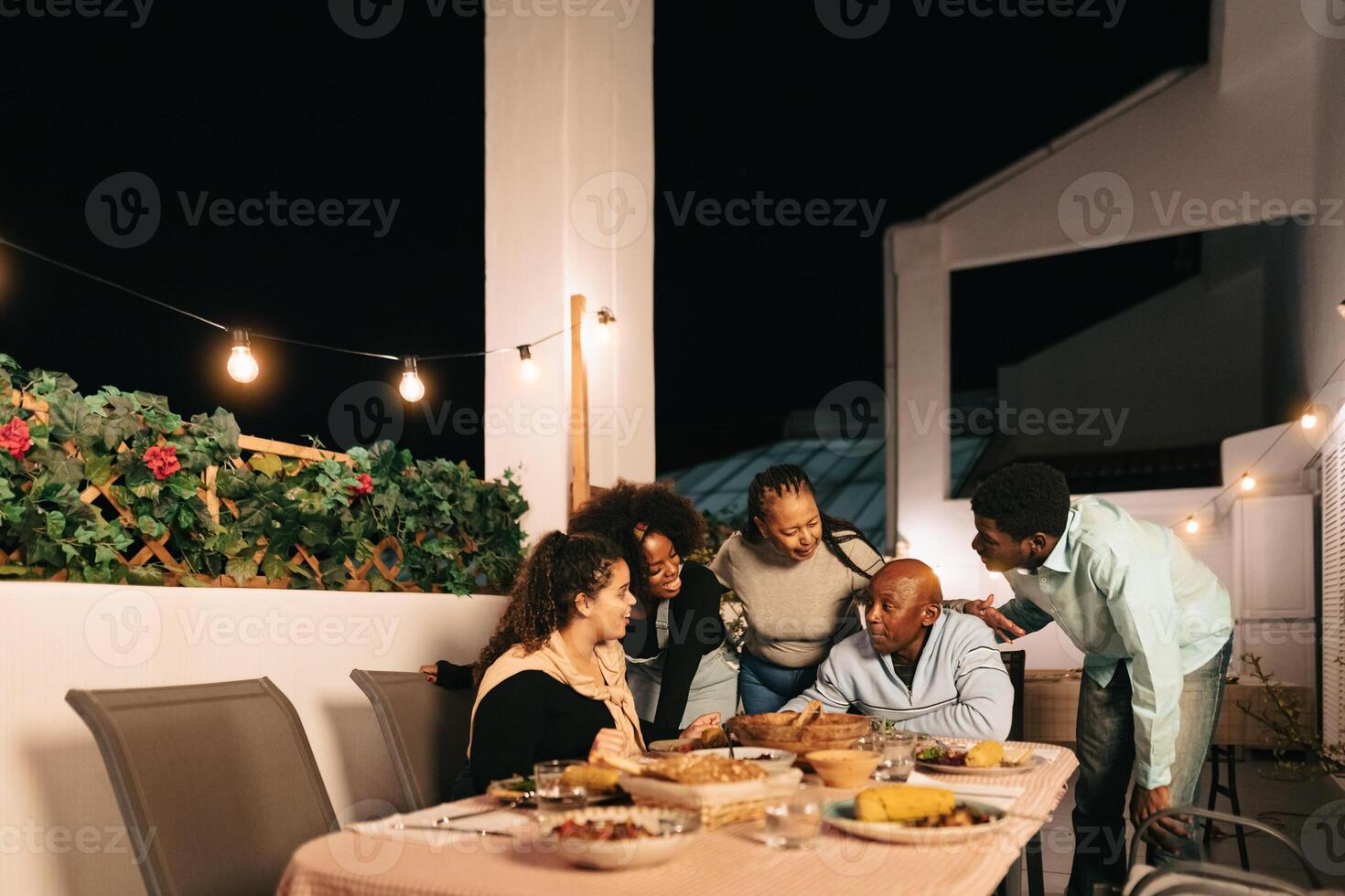 Lycklig afrikansk familj dining tillsammans på hus uteplats foto