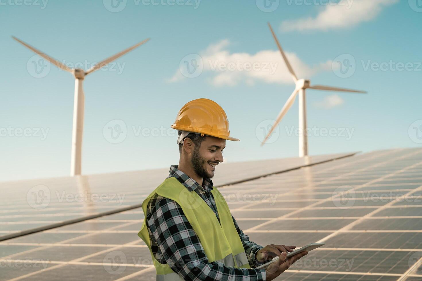 ung ingenjör tittar på på digital läsplatta de ny grön planen för alternativ energi med vind turbin och sol- panel - innovation och grön kraft begrepp foto