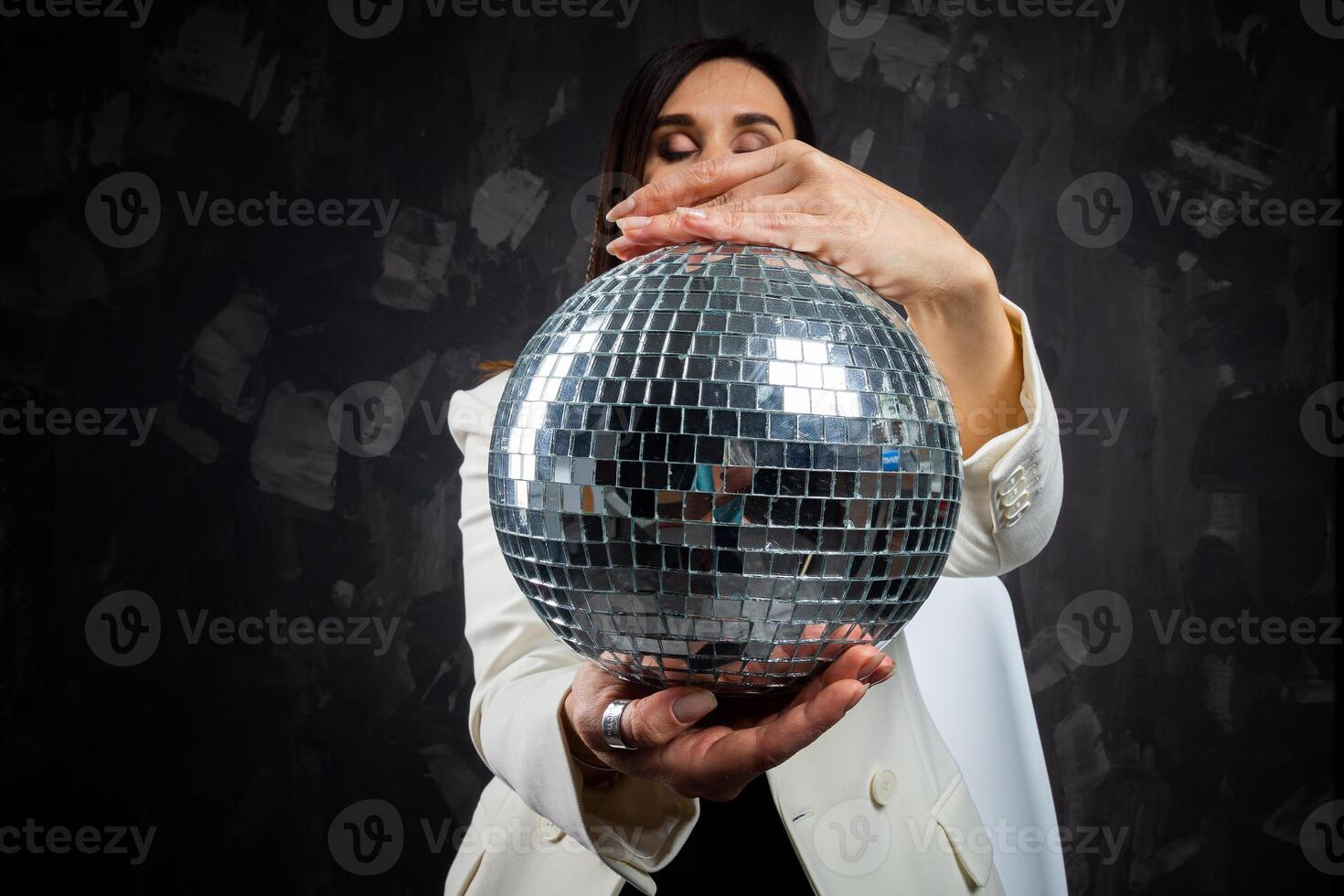 porträtt av en kvinna innehav en silver- disko boll. tagen i en Foto studio.