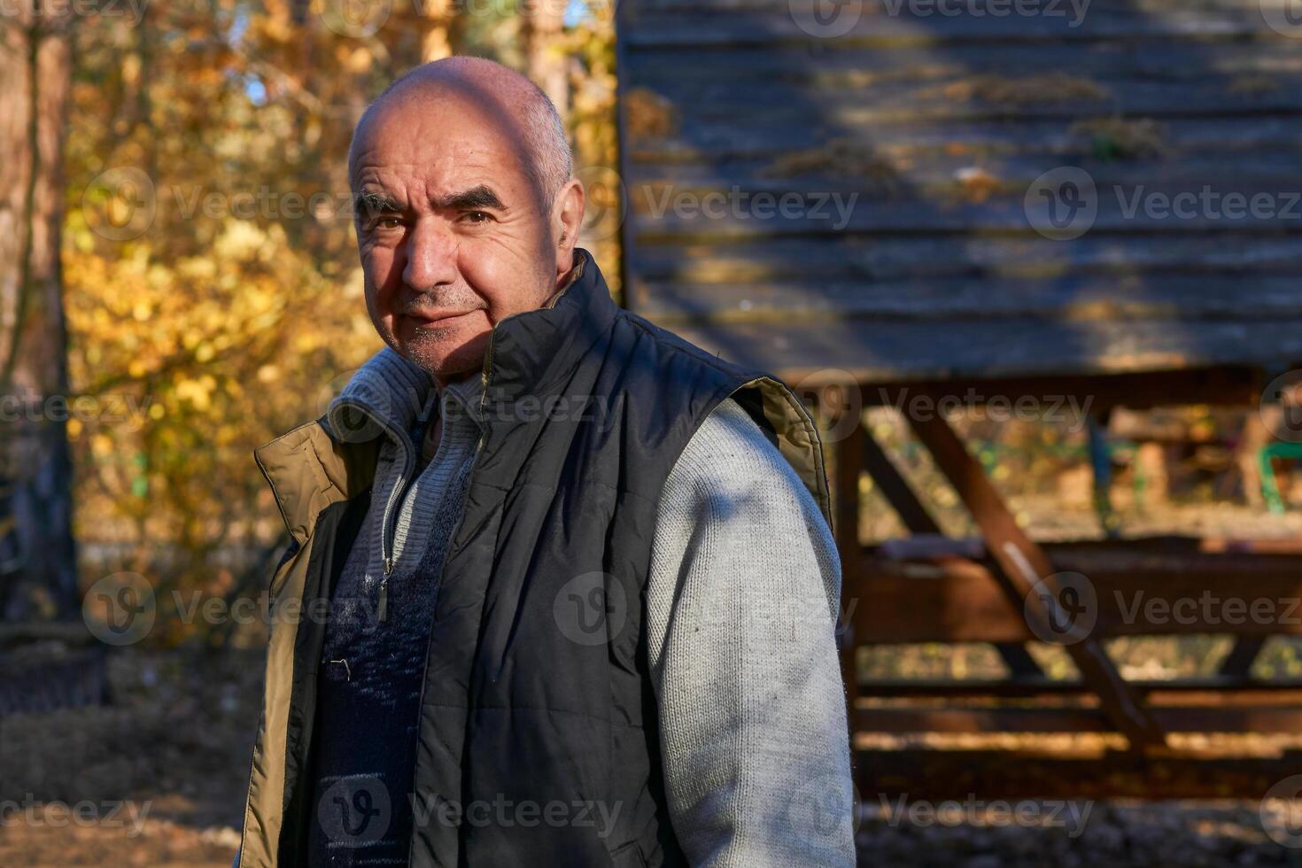 glad äldre pensionär i en värma väst på en campingplats på ett höst picknick foto