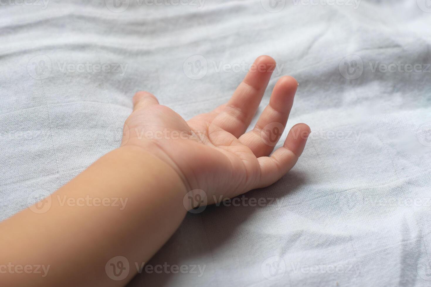 närbild av mjuk bebis händer på madrass. foto