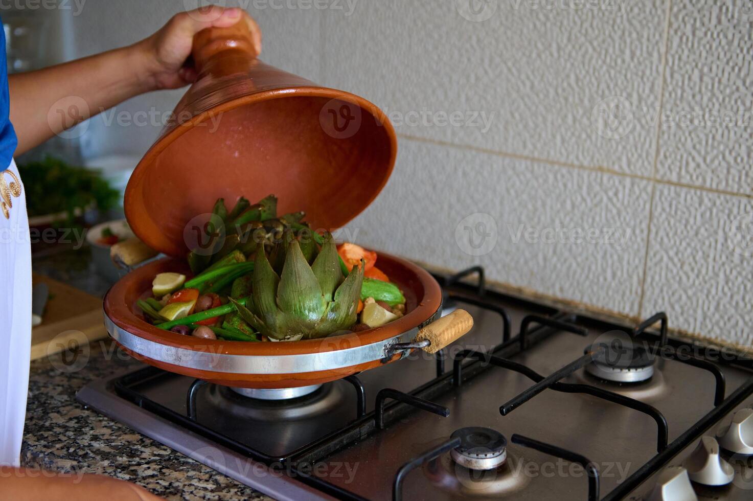 närbild av en hemmafru matlagning grönsaker i tagine lera maträtt på Hem kök foto