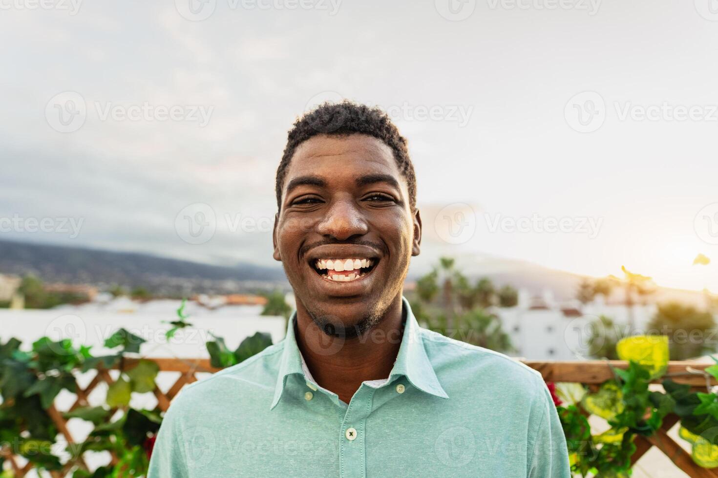 Lycklig ung afrikansk man har roligt leende i främre av kamera på hus uteplats foto