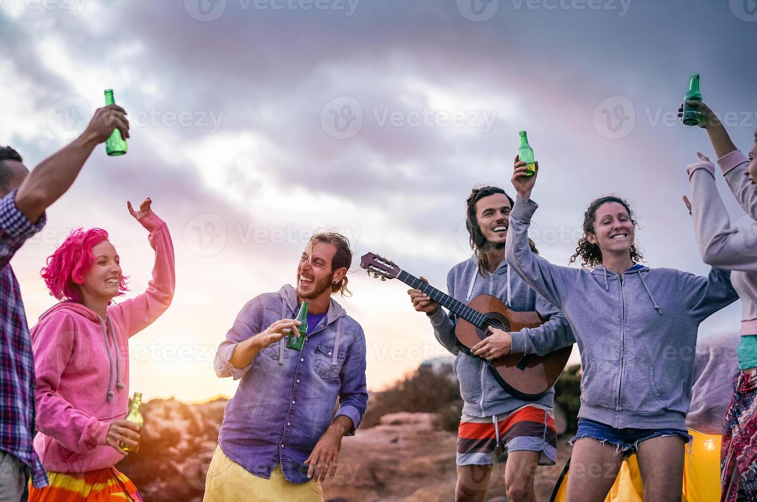 Lycklig vänner framställning fest på solnedgång medan camping Nästa de strand - ung människor har roligt dans och dricka öl utomhus- - tusenårig, sommar, semester och ungdom högtider livsstil begrepp foto