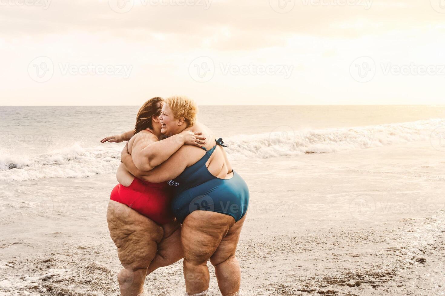Lycklig plus storlek kvinnor har roligt på solig dag på strand under semester tid foto